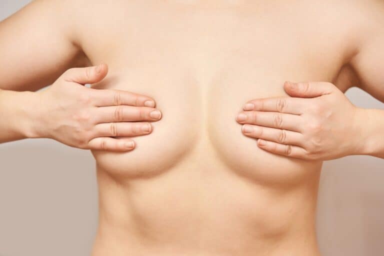 white woman covering her breasts with both hands